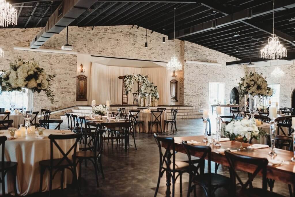 Elegant wedding reception near Fort Worth featuring wooden tables, round tables, crossback chairs and luxury flowers